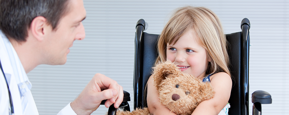 Health care personnel having eye contact with smiling little girl who is holding a tebby bear
